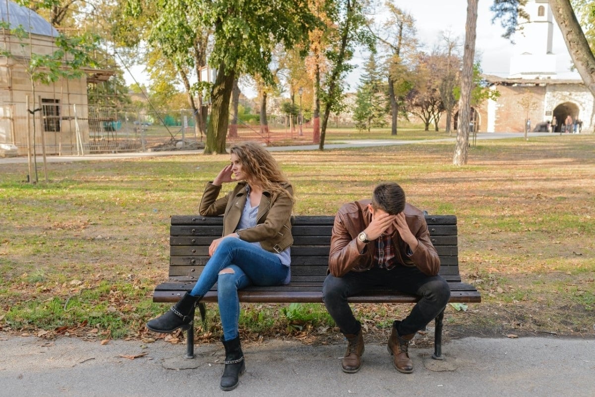 couple sitting on park bench having argument